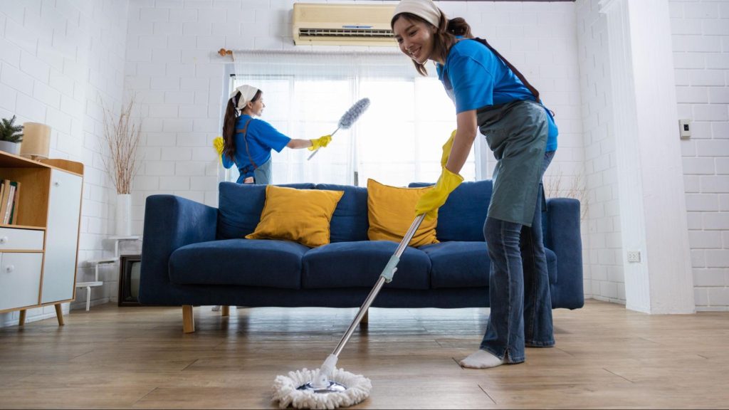 Cleaning team mopping and dusting a bright Miami apartment living room during deep clean