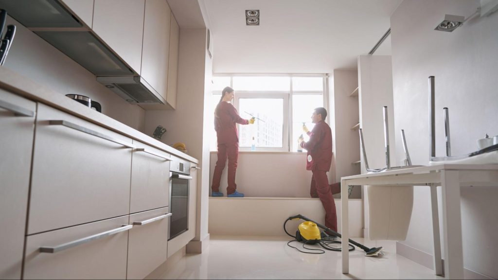 Professional cleaners performing deep cleaning in a bright modern Miami apartment kitchen